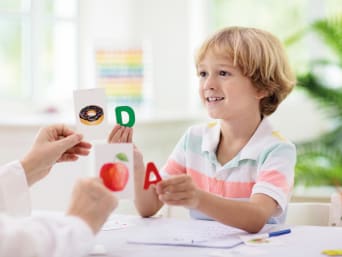 Leertechnieken voor leerlingen - jongen wijst letters toe aan voedsel. Leertechnieken voor leerlingen - jongen wijst letters toe aan voedsel.