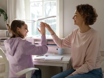 Gute Lernatmosphäre – Mutter und Tochter klatschen sich nach den Hausaufgaben ab. Gute Lernatmosphäre – Mutter und Tochter klatschen sich nach den Hausaufgaben ab.