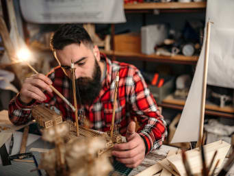 Hobby für Erwachsene: Mann arbeitet an einem Modellschiff aus Holz. Hobby für Erwachsene: Mann arbeitet an einem Modellschiff aus Holz.