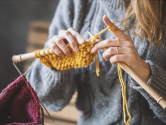 Stricken lernen – Eine Frau strickt mit gelber Wolle. Stricken lernen – Eine Frau strickt mit gelber Wolle.