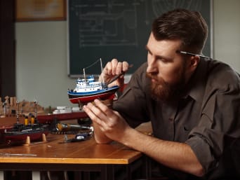 Modellbau – Mann arbeitet an seinem Modellschiff. Modellbau – Mann arbeitet an seinem Modellschiff.