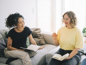 Neue Sprache lernen: Zwei Freundinnen lesen gemeinsam aus einem Buch vor.