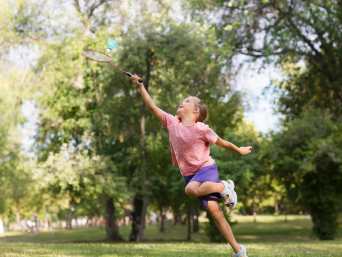 Badminton Kinder: Ein Mädchen springt in die Luft und erreicht mit ihrem Schläger noch den Federball. Badminton Kinder: Ein Mädchen springt in die Luft und erreicht mit ihrem Schläger noch den Federball.