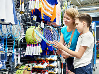 Badmintonschläger für Kinder: Mutter und Sohn betrachten verschiedene Badmintonschläger in einem Fachgeschäft. Badmintonschläger für Kinder: Mutter und Sohn betrachten verschiedene Badmintonschläger in einem Fachgeschäft.