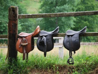 Reiten für Kinder – Pferdesättel auf einem Zaun. Reiten für Kinder – Pferdesättel auf einem Zaun.
