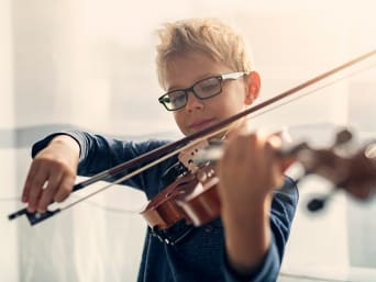 Hobbys für Kinder fördern die Entwicklung – Bub spielt Violine. Hobbys für Kinder fördern die Entwicklung – Bub spielt Violine.
