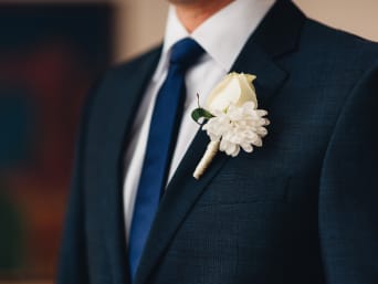 Suits for grooms: a close-up of a flower pin on a suit. Suits for grooms: a close-up of a flower pin on a suit.