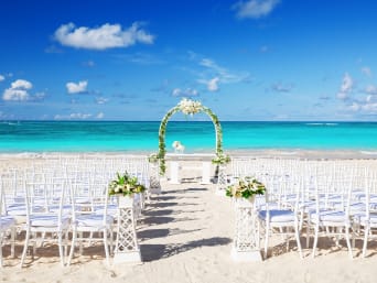Trouwen in het buitenland – witte stoelen en bloemen voor een bruiloft op het strand Trouwen in het buitenland – witte stoelen en bloemen voor een bruiloft op het strand