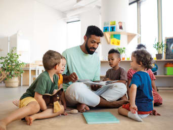Erzieher schaut mit seiner Kindergartengruppe ein Bilderbuch an. Erzieher schaut mit seiner Kindergartengruppe ein Bilderbuch an.