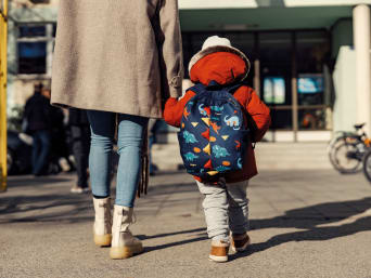 Kindergartentasche – Mutter bringt ihr Kind in den Kindergarten.