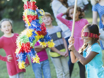Verjaardagspelletjes voor kinderen: Geblinddoekt meisje staat voor piñata. Verjaardagspelletjes voor kinderen: Geblinddoekt meisje staat voor piñata.
