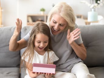 Gifts for children aged 2 and over. A granddaughter opens a present from her grandmother. Gifts for children aged 2 and over. A granddaughter opens a present from her grandmother.