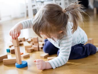 Geschenke für Kleinkinder: Kleines Mädchen baut einen Turm aus Holzbausteinen. Geschenke für Kleinkinder: Kleines Mädchen baut einen Turm aus Holzbausteinen.