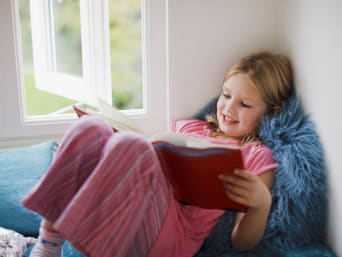 Geschenk 7-Jährige: Kleines Mädchen sitzt an ihrem Fenster und liest in einem Buch. Geschenk 7-Jährige: Kleines Mädchen sitzt an ihrem Fenster und liest in einem Buch.