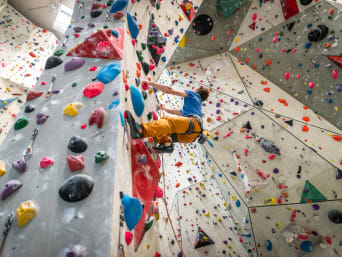Kletterhalle – Mann klettert im Vorstieg die Kletterwand hoch. Kletterhalle – Mann klettert im Vorstieg die Kletterwand hoch.