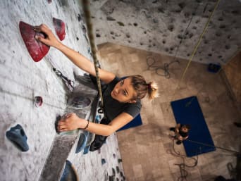 Kletterwand Indoor – Junge Frau klettert im Toprope an der Kletterwand. Kletterwand Indoor – Junge Frau klettert im Toprope an der Kletterwand.