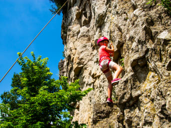Klettern für Kinder: Mädchen klettert an einem Felsen. Klettern für Kinder: Mädchen klettert an einem Felsen.