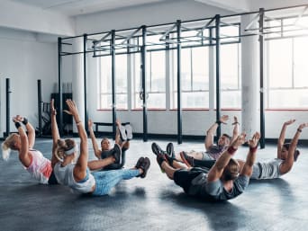 Krafttraining für Läufer: Sportgruppe führt einen Hollow Hold bei einem Core-Workout im Fitnessstudio aus. Krafttraining für Läufer: Sportgruppe führt einen Hollow Hold bei einem Core-Workout im Fitnessstudio aus.