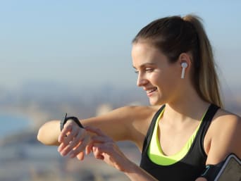 Running training plan for beginners: a woman checking her pulse with a sports watch during her running training. Running training plan for beginners: a woman checking her pulse with a sports watch during her running training.