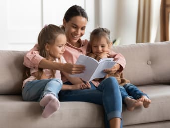 Leren lezen door voor te lezen: moeder leest haar dochters voor. Leren lezen door voor te lezen: moeder leest haar dochters voor.