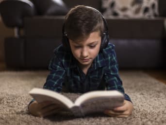 Kinder zum Lesen motivieren: Junge hört ein Hörbuch und liest nebenbei still mit. Kinder zum Lesen motivieren: Junge hört ein Hörbuch und liest nebenbei still mit.
