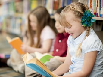 Mädchen liest mit Freunden in der Bibliothek. Mädchen liest mit Freunden in der Bibliothek.