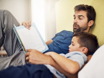 Voorlezen: Vader leest zijn zoontje uit een kinderboek voor. Voorlezen: Vader leest zijn zoontje uit een kinderboek voor.