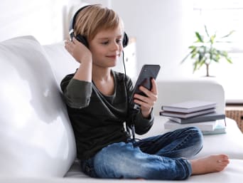 Handy kindersicher machen – Junge hört Musik mit seinem Smartphone. Handy kindersicher machen – Junge hört Musik mit seinem Smartphone.