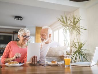 Internetsicherheit – älteres Paar liest während des Frühstücks auf einem Tablet. Internetsicherheit – älteres Paar liest während des Frühstücks auf einem Tablet.