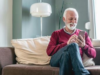 Mann sitzt auf der Couch und sieht sich Angebote auf dem Handy an. Mann sitzt auf der Couch und sieht sich Angebote auf dem Handy an.