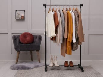 Summer to winter capsule wardrobe: different items of clothing hung up on a clothes rack.  Summer to winter capsule wardrobe: different items of clothing hung up on a clothes rack.