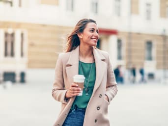Clothing for tall women: a woman wearing a coat walking through the city.  Clothing for tall women: a woman wearing a coat walking through the city.