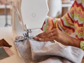 Upcycling ideas for clothes: a woman using spare pieces of fabric to jazz up her old jeans. Upcycling ideas for clothes: a woman using spare pieces of fabric to jazz up her old jeans.