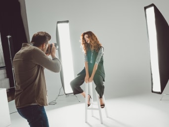 Modefotograf werden: Junger Fotograf shootet weibliches Model in Fotostudio. Modefotograf werden: Junger Fotograf shootet weibliches Model in Fotostudio.