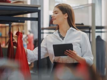 Visual Merchandising Ausbildung: Junge Frau überprüft Warenpräsentation im Laden. Visual Merchandising Ausbildung: Junge Frau überprüft Warenpräsentation im Laden.