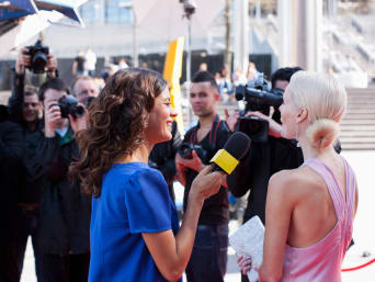 Moderedakteurin interviewt elegant gekleidete Dame auf rotem Teppich. Moderedakteurin interviewt elegant gekleidete Dame auf rotem Teppich.