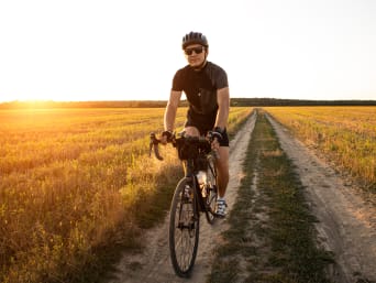 Bikepacking für Anfänger: Radfahrer fährt bei einer Bikepacking-Tour über einen Feldweg. Bikepacking für Anfänger: Radfahrer fährt bei einer Bikepacking-Tour über einen Feldweg.