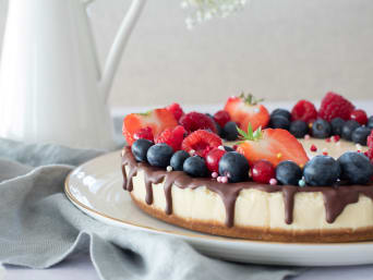 Finished cheesecake with fruit and chocolate icing on the table. Finished cheesecake with fruit and chocolate icing on the table.