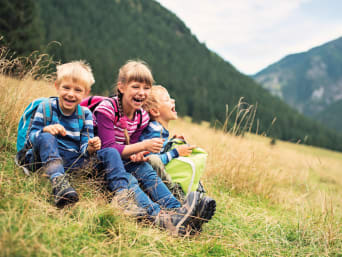 Nachhaltiger Urlaub mit Kindern: Geschwister machen Rast bei einer Wanderung. Nachhaltiger Urlaub mit Kindern: Geschwister machen Rast bei einer Wanderung.