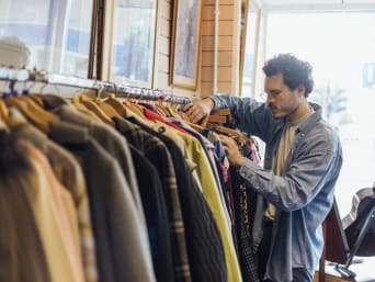 Using clothes in a sustainable way: a man looking at jackets in a second-hand shop. Using clothes in a sustainable way: a man looking at jackets in a second-hand shop.