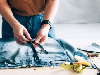 Repairing clothes: a woman is replacing a zip on her pair of jeans. Repairing clothes: a woman is replacing a zip on her pair of jeans.