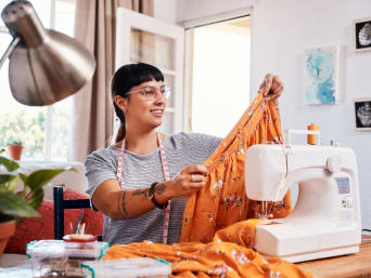 Upcycling ideas for clothes: a woman using spare pieces of material to sew a skirt. Upcycling ideas for clothes: a woman using spare pieces of material to sew a skirt.
