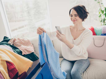 Creating a capsule wardrobe step-by-step: a woman taking photos of her old clothes that she would like to sell. Creating a capsule wardrobe step-by-step: a woman taking photos of her old clothes that she would like to sell.