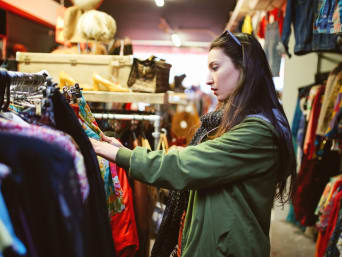 Tips on buying second-hand clothes: a woman looking at clothes in a second-hand shop. Tips on buying second-hand clothes: a woman looking at clothes in a second-hand shop.