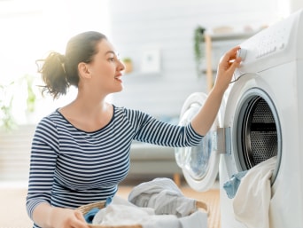 Natural laundry: a woman choosing a wash programme on her washing machine. Natural laundry: a woman choosing a wash programme on her washing machine.