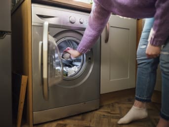 Milieuvriendelijk wassen: vrouw doet was in de wasmachine. Milieuvriendelijk wassen: vrouw doet was in de wasmachine.