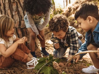 Spiele im Wald – Kinder untersuchen den Waldboden mit einer Lupe. Spiele im Wald – Kinder untersuchen den Waldboden mit einer Lupe.