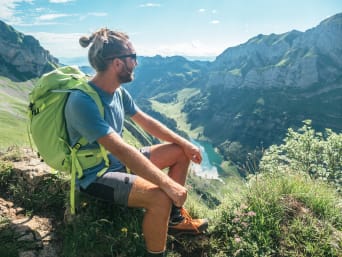 Appenzell Aktivitäten: Wanderer macht Rast auf einem Berggipfel und blickt in das Tal.  Appenzell Aktivitäten: Wanderer macht Rast auf einem Berggipfel und blickt in das Tal.