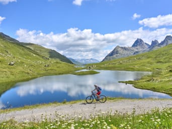 Mountainbiken Tirol: Frau fährt mit dem Fahrrad an einem See vorbei. Mountainbiken Tirol: Frau fährt mit dem Fahrrad an einem See vorbei.