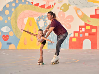 Rollkunstlauf lernen – Mädchen übt eine Standwaage mit ihrer Trainerin. Rollkunstlauf lernen – Mädchen übt eine Standwaage mit ihrer Trainerin.